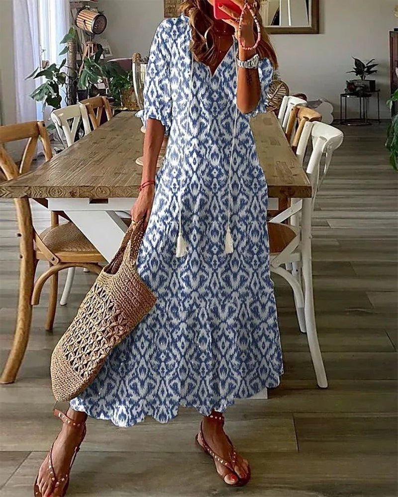 A woman wearing the Fiona boho midi dress with tassel ties at the neckline and a ruffled skirt.
