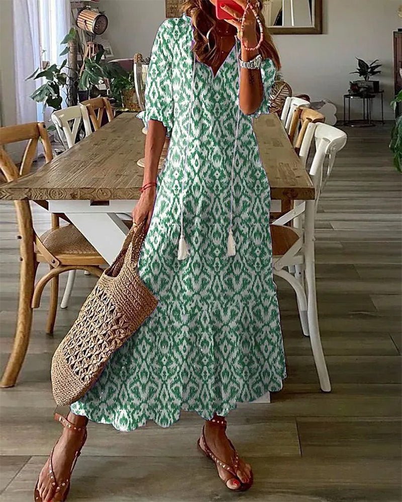 A woman wearing the Fiona boho midi dress with tassel ties at the neckline and a ruffled skirt.