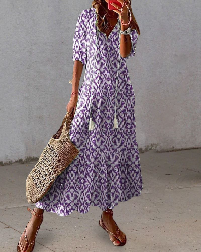 Woman wearing the Colette™ boho maxi dress with fringe details and a V-neckline, relaxed in a warm outdoor setting.