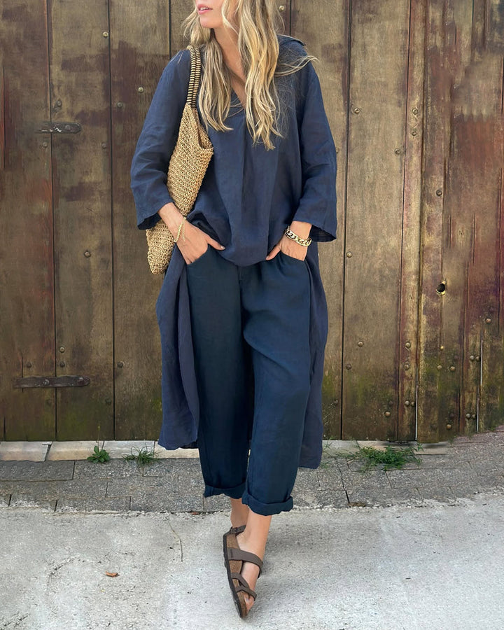 A woman wearing a blue asymmetric tunic with wide-leg trousers