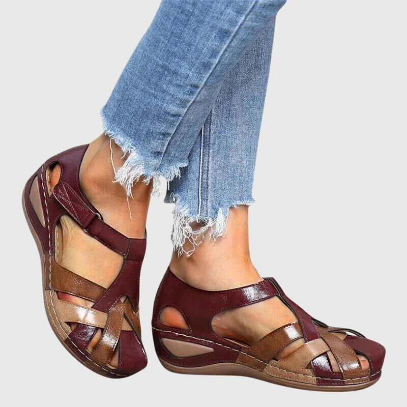 A woman in burgundy comfort sandals walking with ease on a sunny day, feet relaxed and supported.