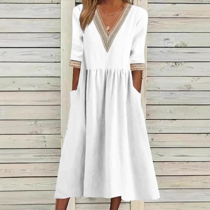 A woman wearing the Deirdre V-neck midi dress with delicate detailing at the collar and sleeves.