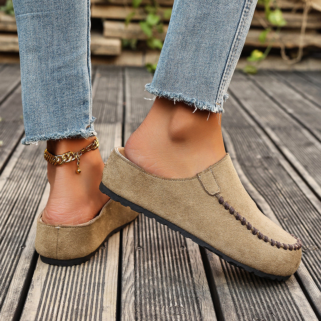 A pair of minimal slip-on loafers in warm brown with a soft footbed and open back