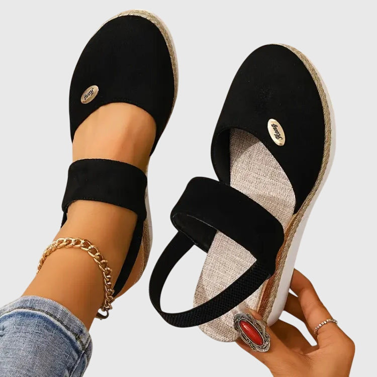 A woman walking comfortably in black cushioned support sandals with adjustable straps.