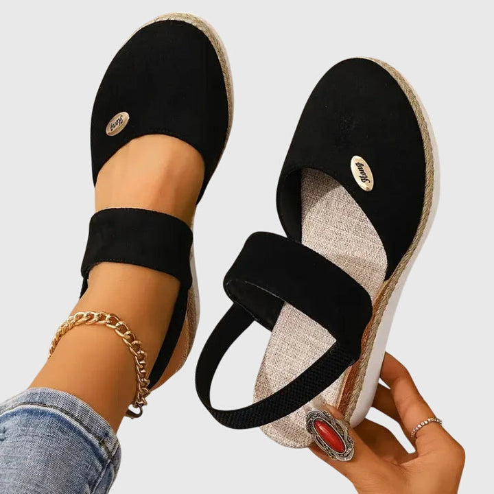A woman walking comfortably in black cushioned support sandals with adjustable straps.