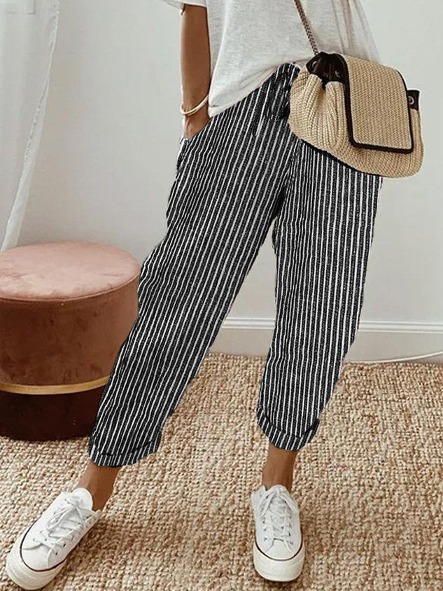 A woman wearing flowing elegant trousers with a soft elastic waist and deep pockets.