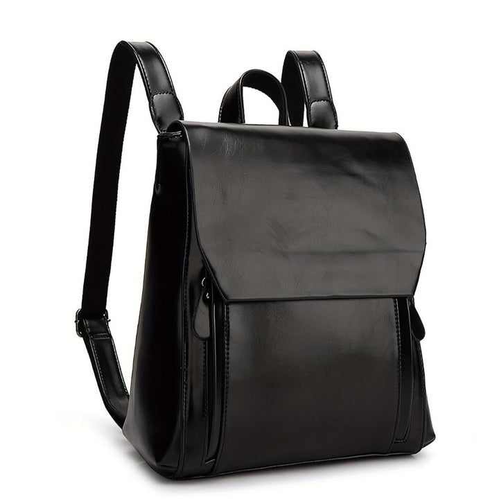 A woman wearing a padded vintage-style backpack over both shoulders while walking through the city.