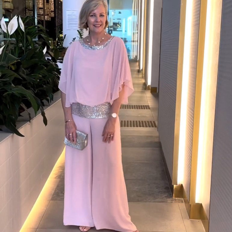 A woman wearing an embellished blouse-style top with softly flowing wide evening trousers.