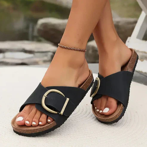 Black flat sandals with wide strap and decorative buckle detail