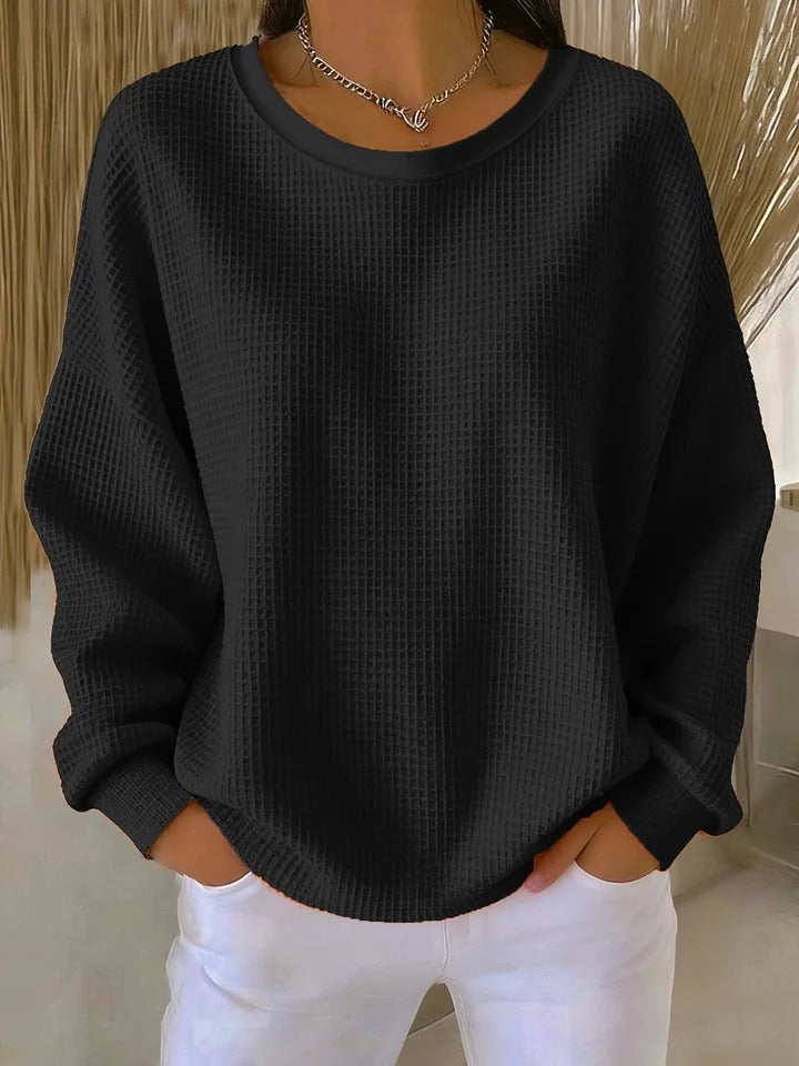 A woman wearing a relaxed-fit waffle-stitch jumper in soft pink with a textured surface