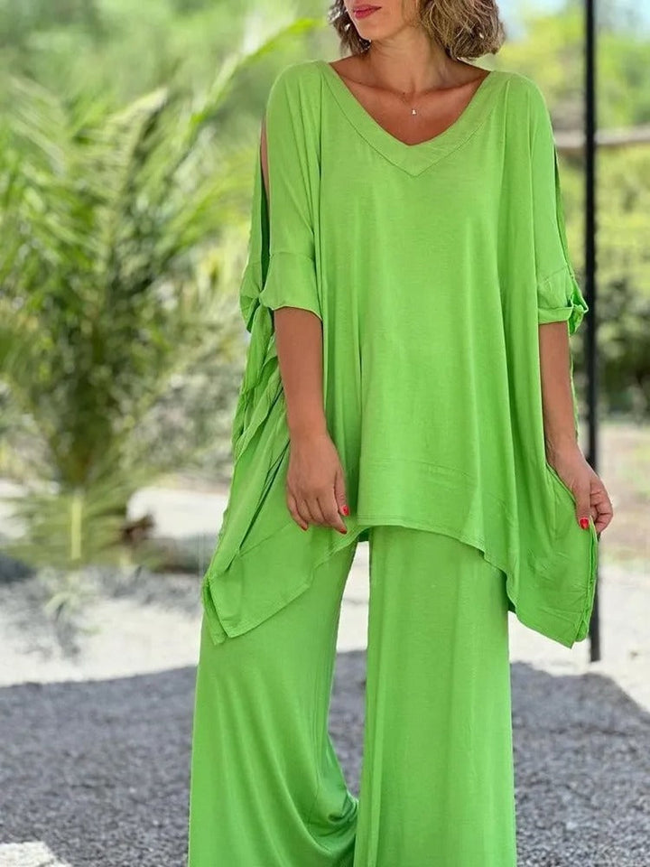 A woman wearing a draped top with shoulder cut-out details and matching wide trousers.