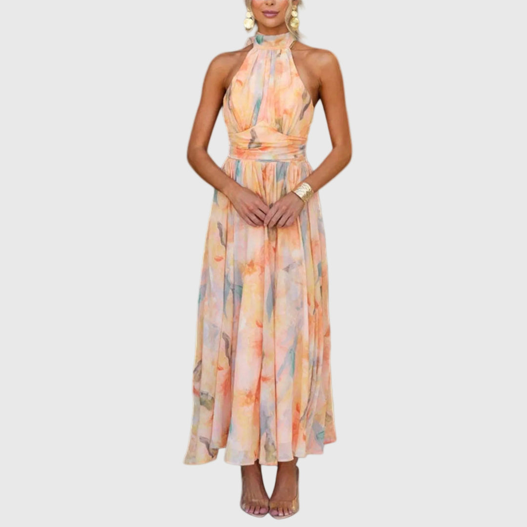 Woman wearing the Rachel halterneck maxi dress in warm watercolour tones at an outdoor celebration.