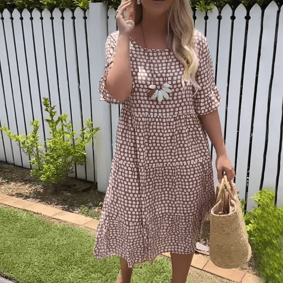 A woman wearing the Angela short sleeve midi dress with a flowing skirt on a warm day.