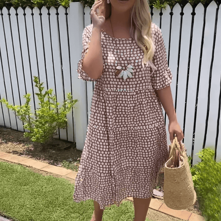 A woman wearing the Angela short sleeve midi dress with a flowing skirt on a warm day.