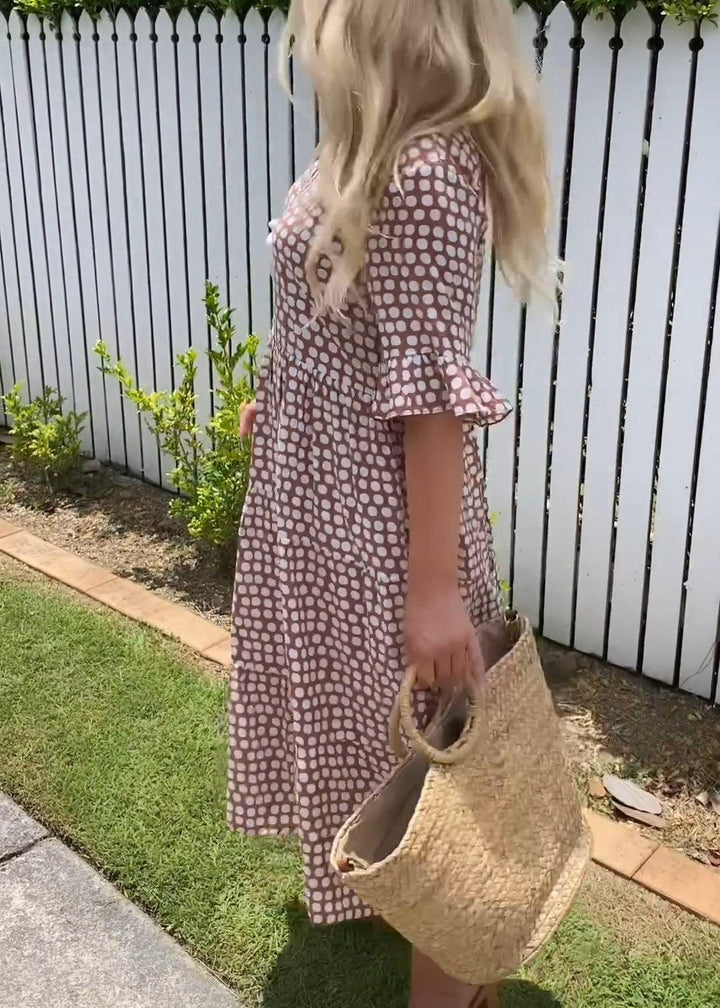 Woman wearing the Rita™ polka dot midi dress with short sleeves, relaxed and smiling in a summer setting.
