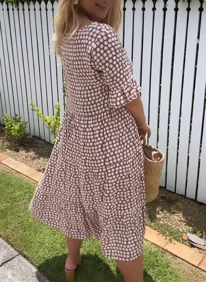 A woman wearing the Angela short sleeve midi dress with a flowing skirt on a warm day.