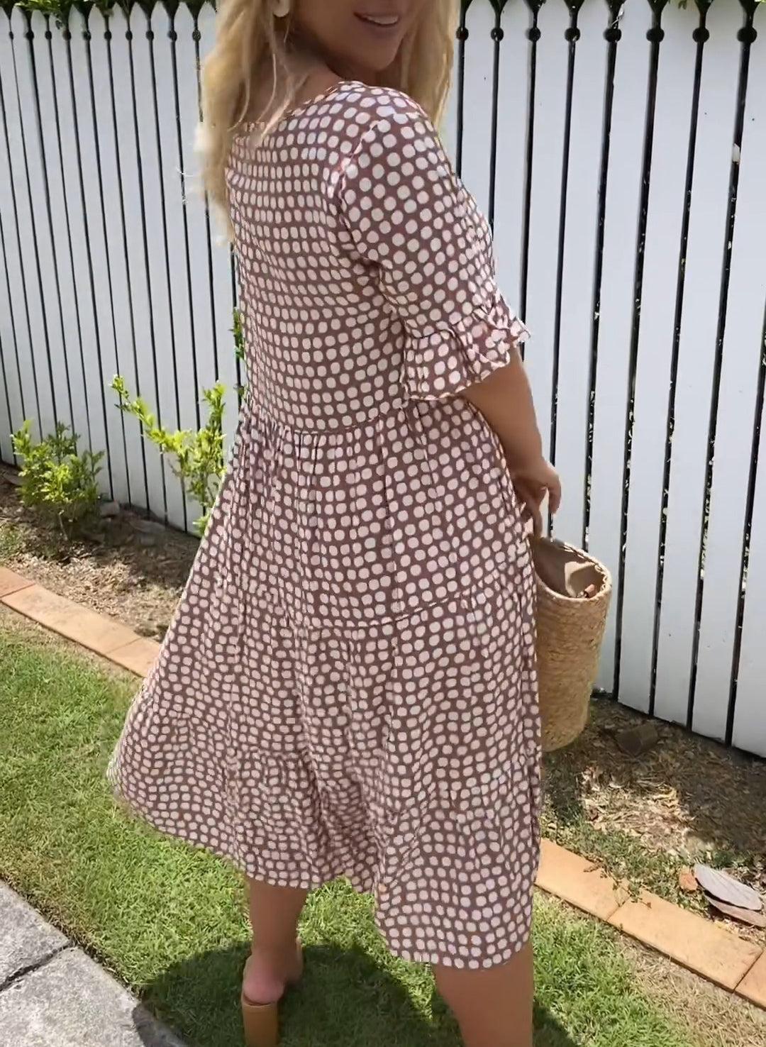 Woman wearing the Rita™ polka dot midi dress with short sleeves, relaxed and smiling in a summer setting.