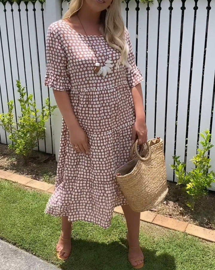 Woman wearing the Rita™ polka dot midi dress with short sleeves, relaxed and smiling in a summer setting.