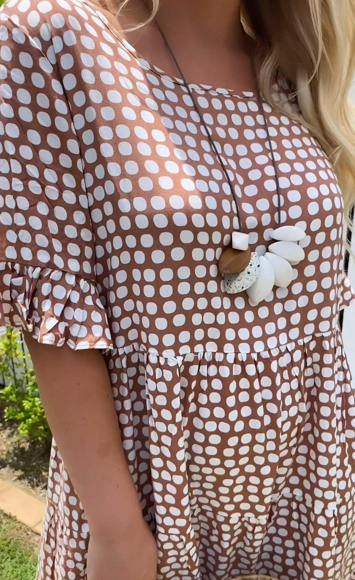 Woman wearing the Rita™ polka dot midi dress with short sleeves, relaxed and smiling in a summer setting.