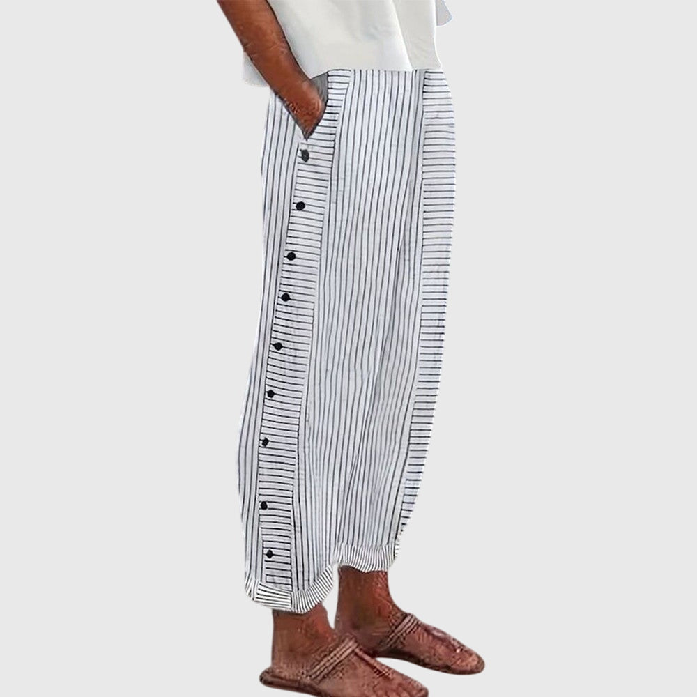 A woman wearing elegant everyday trousers in a fine blue stripe with a wide cut and side buttons.