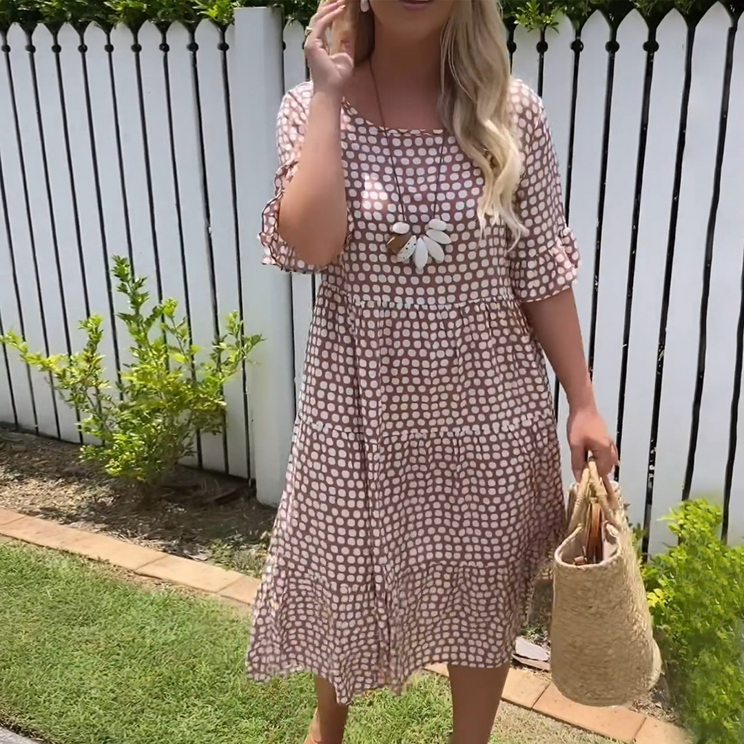 Woman wearing the Rita™ polka dot midi dress with short sleeves, relaxed and smiling in a summer setting.