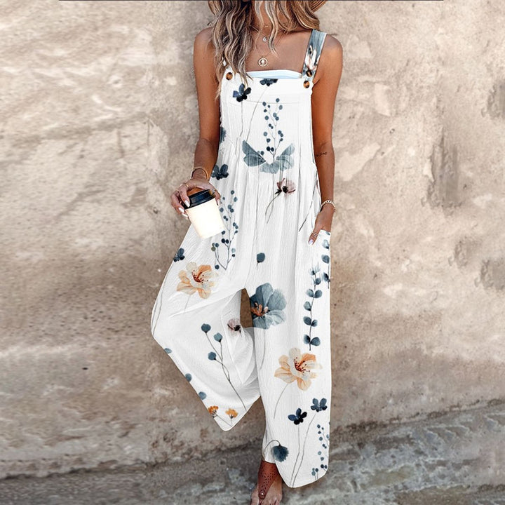 A woman wearing elegant black dungarees with a single large cream bloom and adjustable straps.