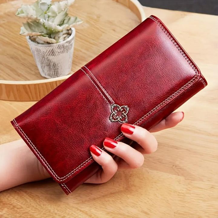 A woman holding a long flap-over wallet, tucking a card into its slot.