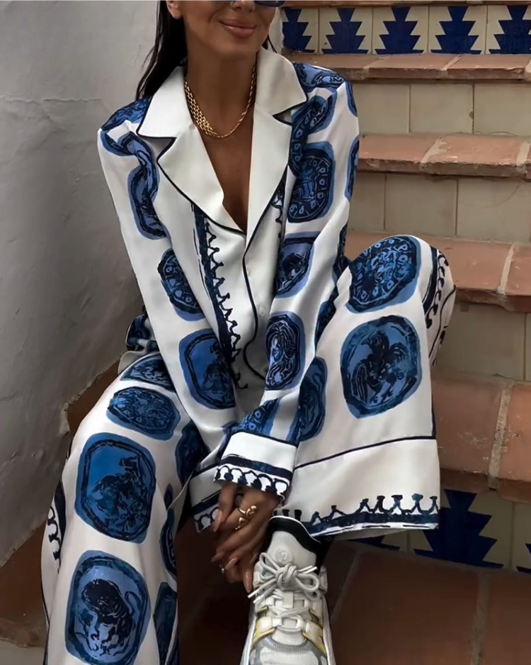 A woman wearing a blue-and-white printed open-collar shirt and matching straight-leg trousers on a warm summer day