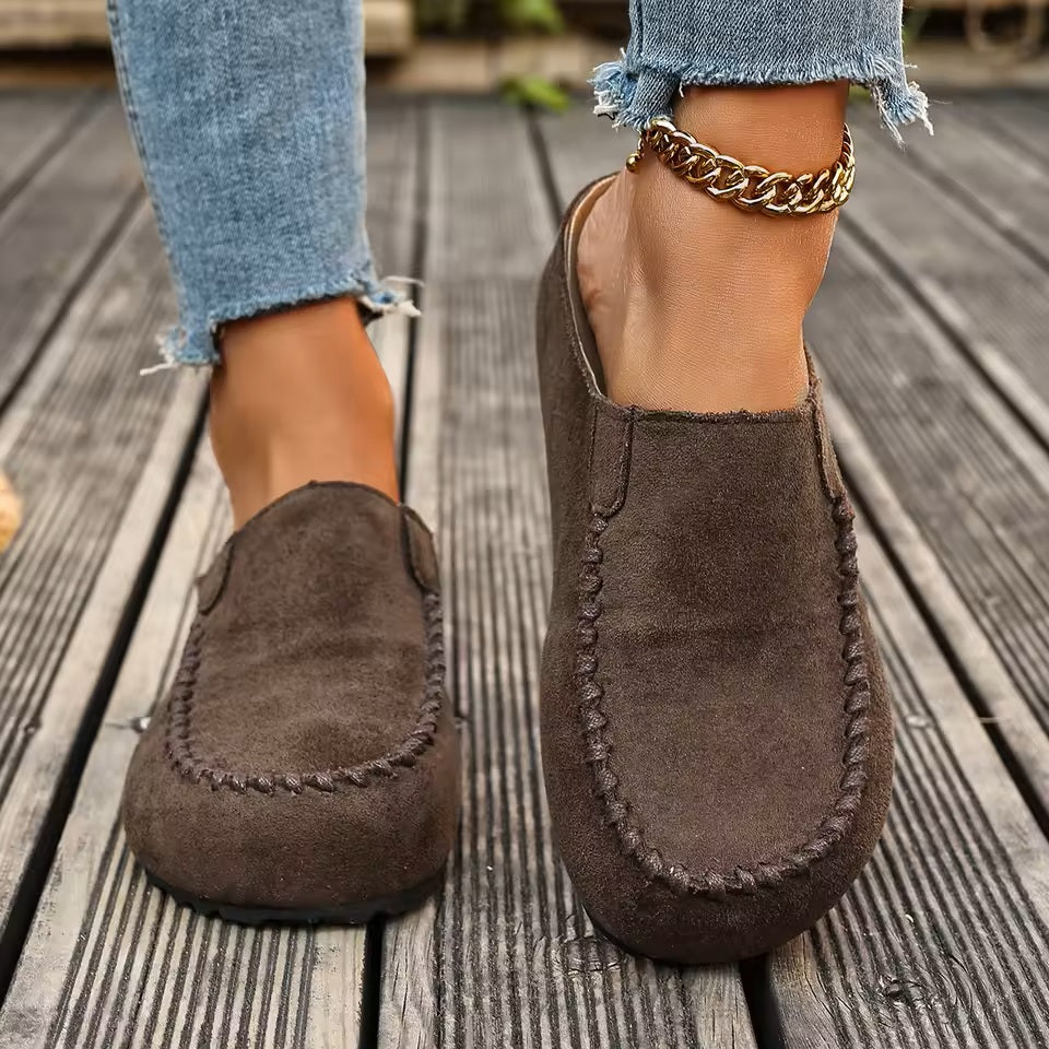 A pair of minimal slip-on loafers in warm brown with a soft footbed and open back