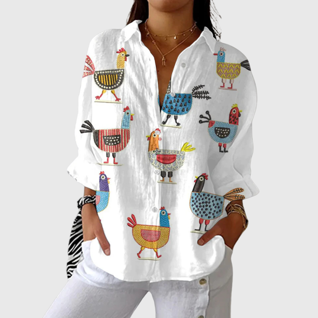 A woman wearing a loose colourful printed blouse with adjustable sleeves, styled with trousers for a comfortable day out.
