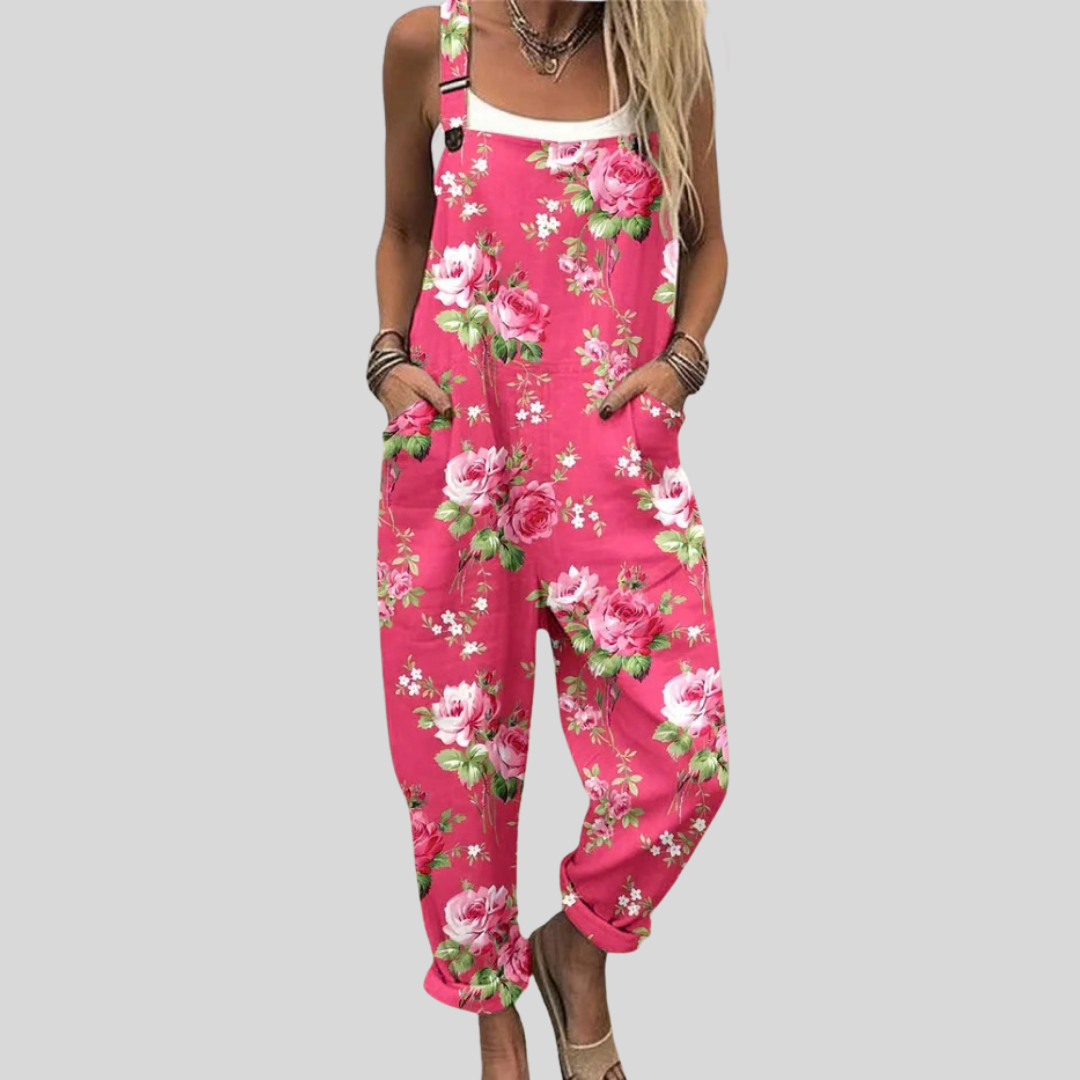 Vivid fuchsia dungarees covered in large deep cerise peony and rose blooms with green leaves, adjustable straps and side pockets.