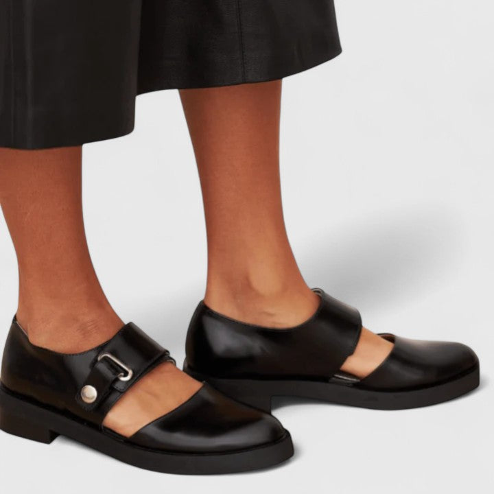 Black wide-strap Mary Jane shoes with a rounded toe and metal buckle detail