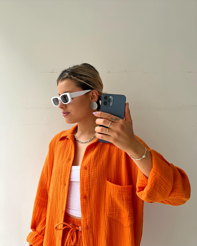 A woman wearing a relaxed button shirt with matching drawstring shorts, fresh and easy.
