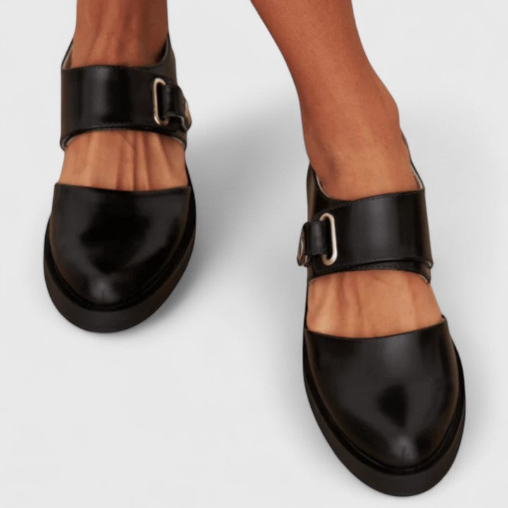 Black wide-strap Mary Jane shoes with a rounded toe and metal buckle detail