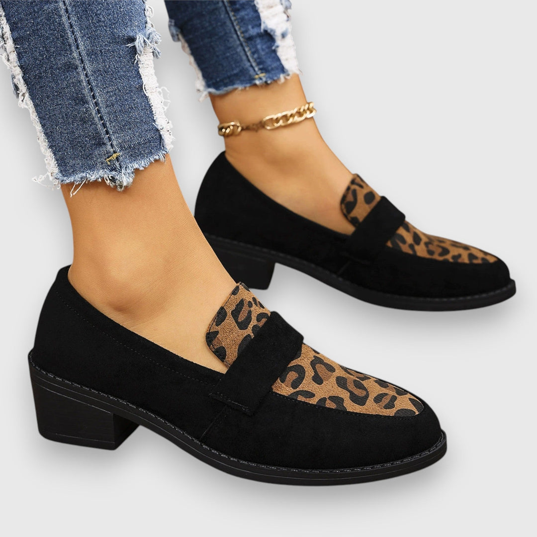 A woman wearing tan leopard print loafers with a low block heel, styled with jeans.