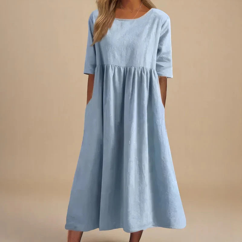 A woman wearing the Carmel flowing day dress with a gathered waist and elbow-length sleeves.