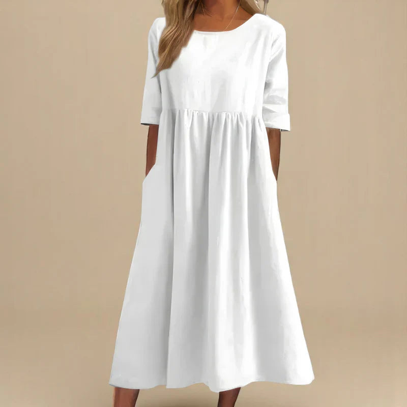 A woman wearing the Carmel flowing day dress with a gathered waist and elbow-length sleeves.