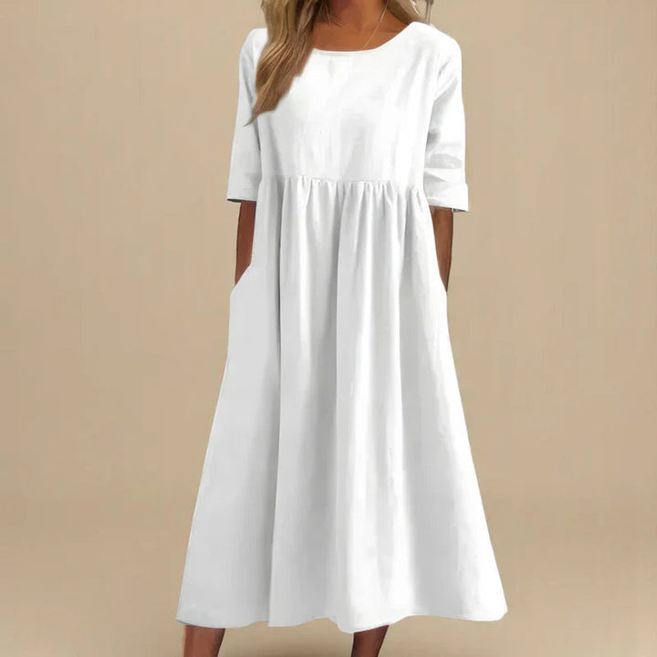 A woman wearing the Carmel flowing day dress with a gathered waist and elbow-length sleeves.