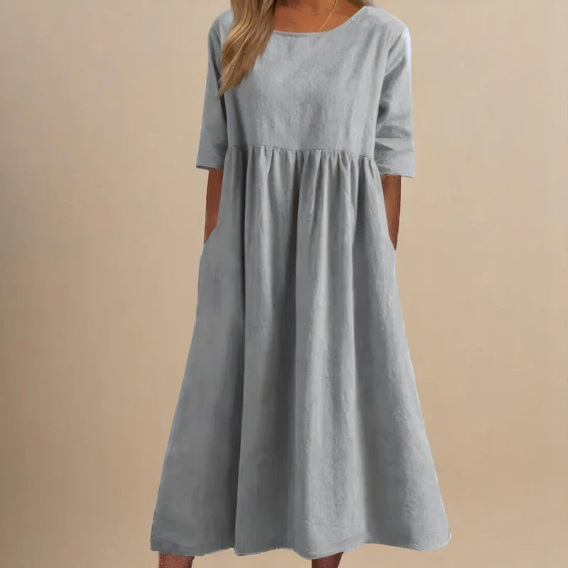 A woman wearing the Carmel flowing day dress with a gathered waist and elbow-length sleeves.