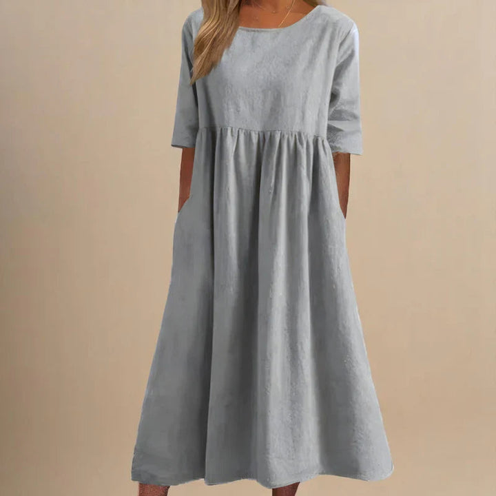 A woman wearing the Carmel flowing day dress with a gathered waist and elbow-length sleeves.