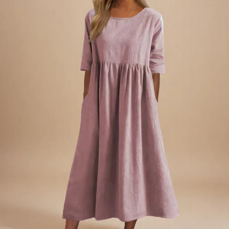A woman wearing the Carmel flowing day dress with a gathered waist and elbow-length sleeves.