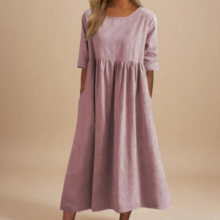 A woman wearing the Carmel flowing day dress with a gathered waist and elbow-length sleeves.