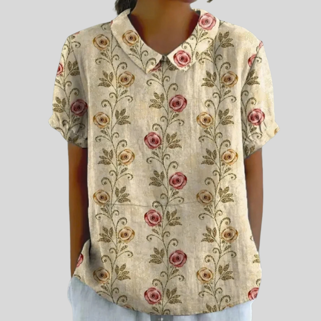 A woman wearing a floral top with an elegant polo collar, styled neatly with trousers for an easy, put-together look.