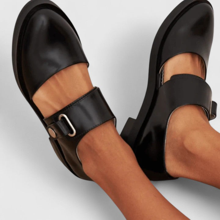 Black wide-strap Mary Jane shoes with a rounded toe and metal buckle detail