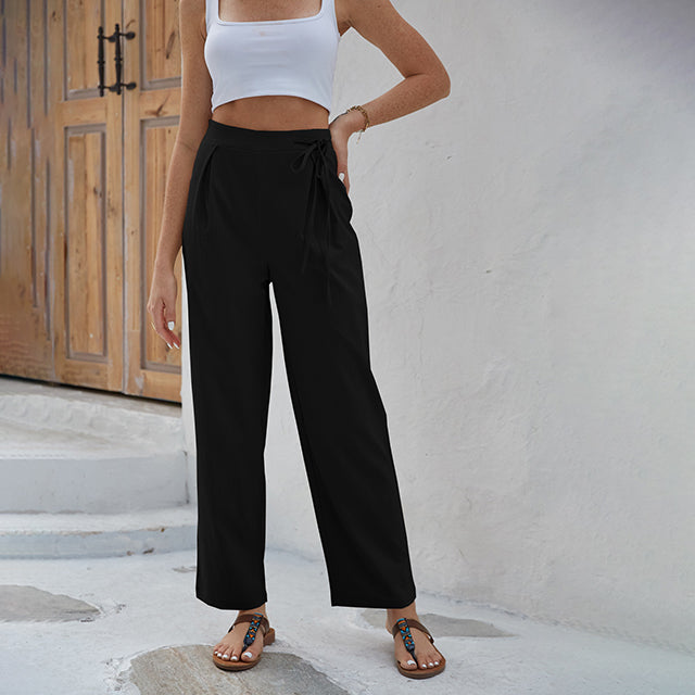 Woman wearing high-waisted wide-leg trousers with a knot detail and a tucked-in top.