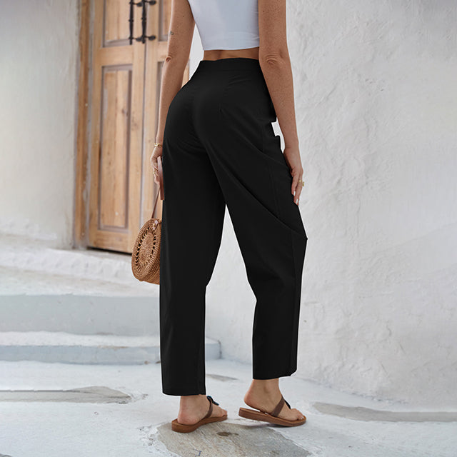 Woman wearing high-waisted wide-leg trousers with a knot detail and a tucked-in top.