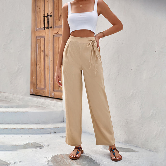 Woman wearing high-waisted wide-leg trousers with a knot detail and a tucked-in top.