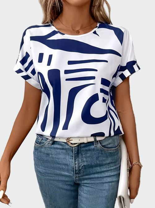 Women's white short-sleeve blouse with a bold blue abstract geometric print and rolled sleeve hems