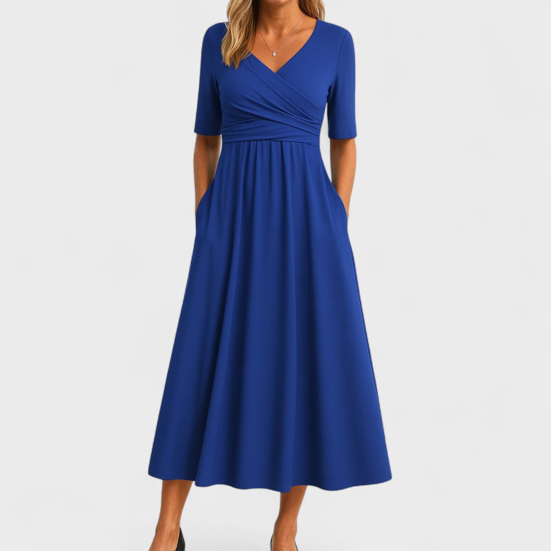 Woman wearing a mid-calf dress with a crossover V-neckline, gathered waist and gently flared skirt.