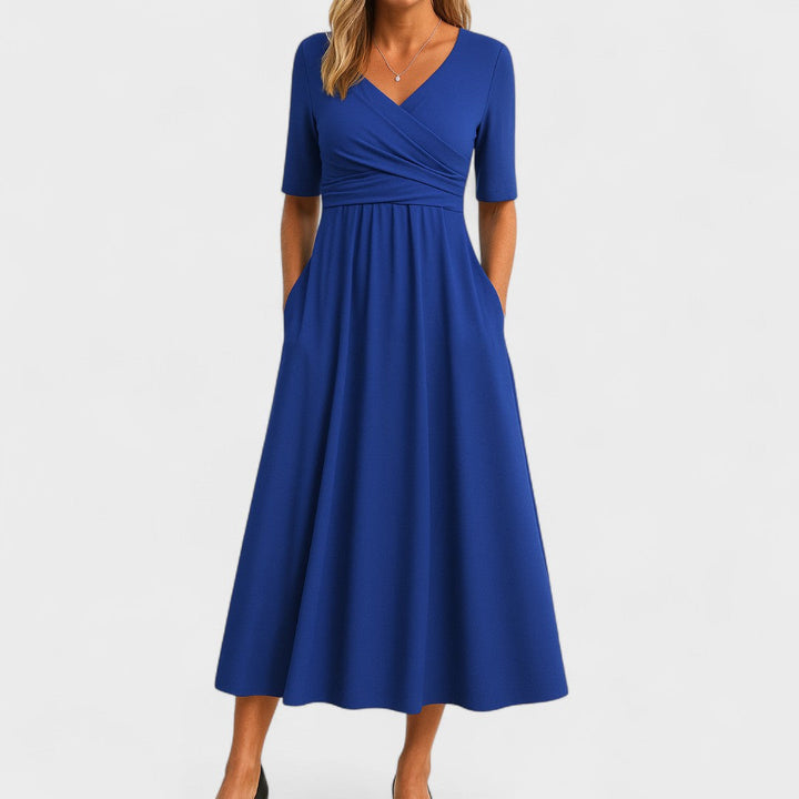 Woman wearing a mid-calf dress with a crossover V-neckline, gathered waist and gently flared skirt.